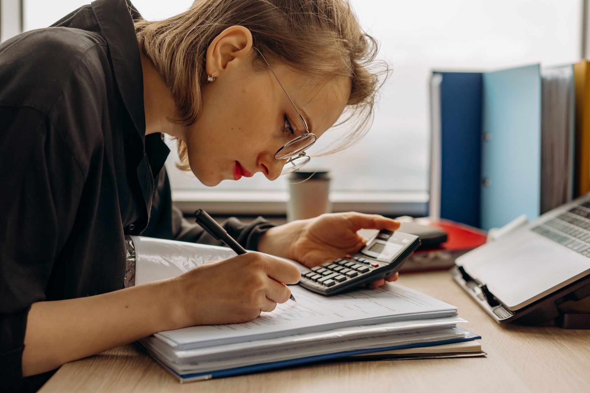 Bookkeeper working through documents with a calculator